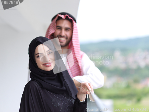 Image of portrait of beautiful arabian couple standing on balcony