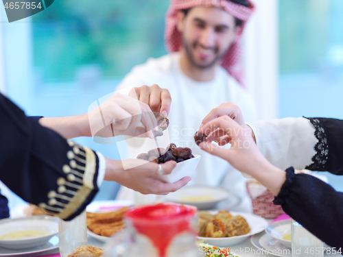 Image of Muslim family having Iftar dinner eating dates to break feast