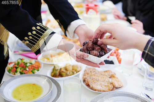 Image of Muslim family having Iftar dinner eating dates to break feast