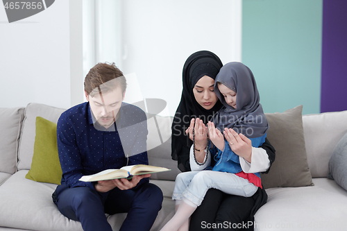 Image of muslim family reading Quran and praying at home