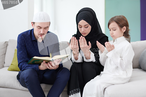 Image of muslim family reading Quran and praying at home