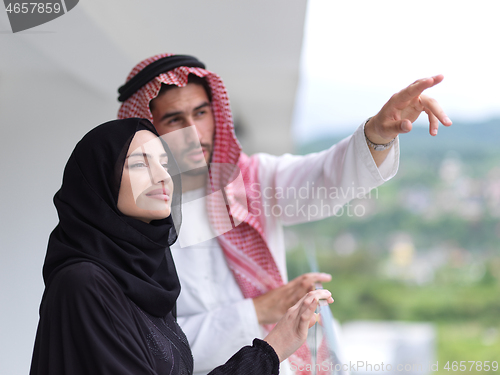 Image of portrait of beautiful arabian couple standing on balcony