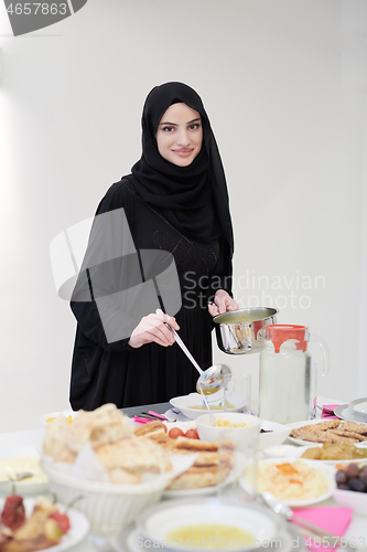 Image of young muslim girl serving food on the table for iftar dinner