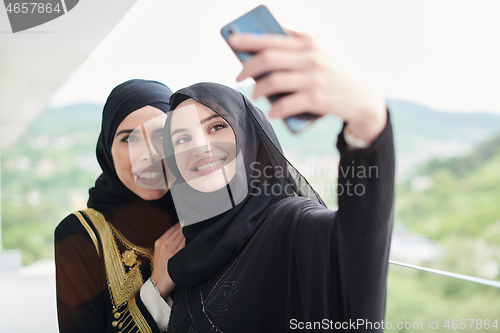 Image of muslim women taking selfie picture on the balcony