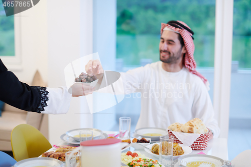 Image of Muslim family having Iftar dinner eating dates to break feast