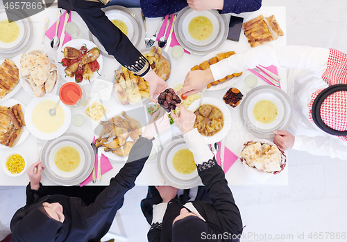 Image of Muslim family having Iftar dinner eating dates to break feast to