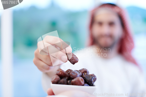 Image of Muslim family having Iftar dinner eating dates to break feast