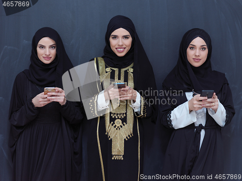 Image of muslim women using mobile phone in front of black chalkboard