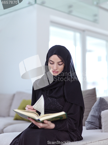 Image of young muslim woman reading Quran at home