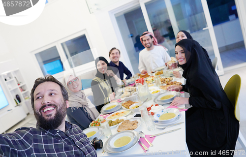 Image of Muslim family having Iftar dinner taking pictures with mobile ph