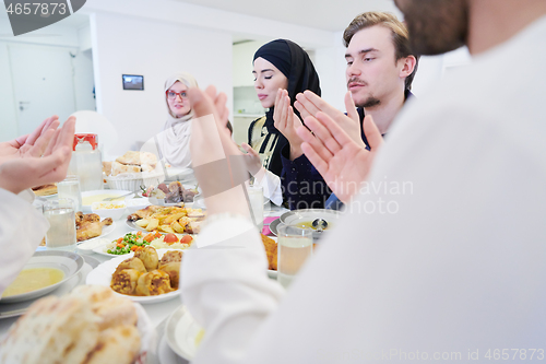 Image of traditional muslim family praying before iftar dinner