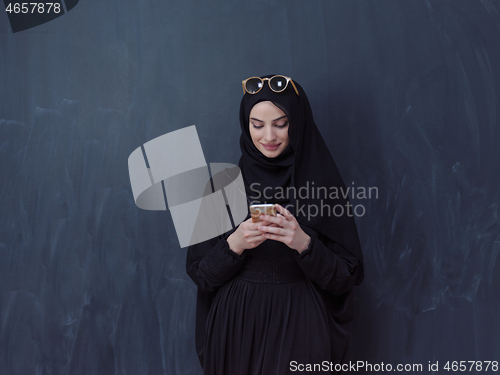 Image of young muslim woman wearing sunglasses using smartphone