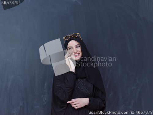 Image of young muslim woman wearing sunglasses using smartphone