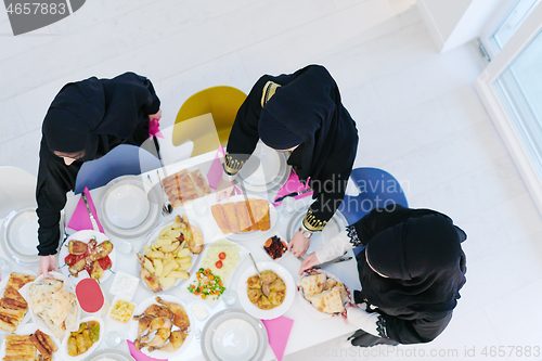 Image of young muslim girls serving food on the table for iftar dinner to