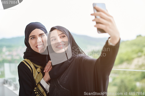 Image of muslim women taking selfie picture on the balcony