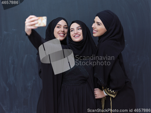 Image of muslim women taking selfie picture in front of black chalkboard