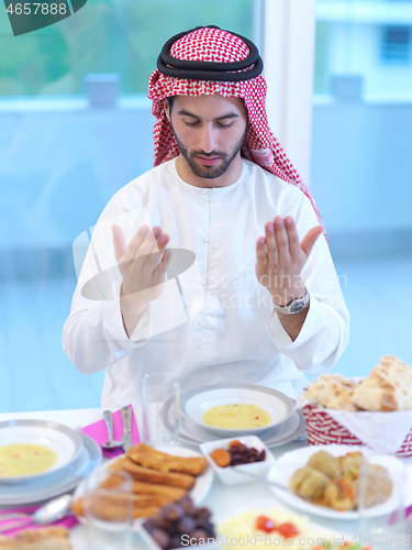 Image of arabian man making traditional prayer to God before iftar dinner