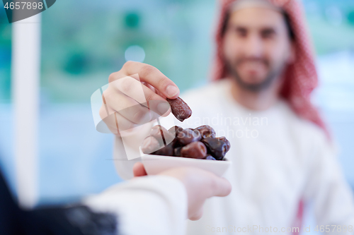 Image of Muslim family having Iftar dinner eating dates to break feast