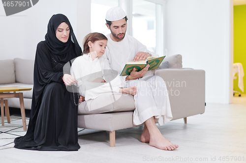 Image of muslim family reading Quran and praying at home