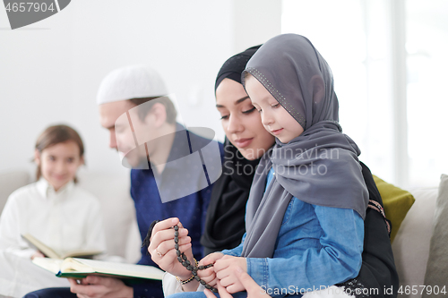 Image of muslim family reading Quran and praying at home