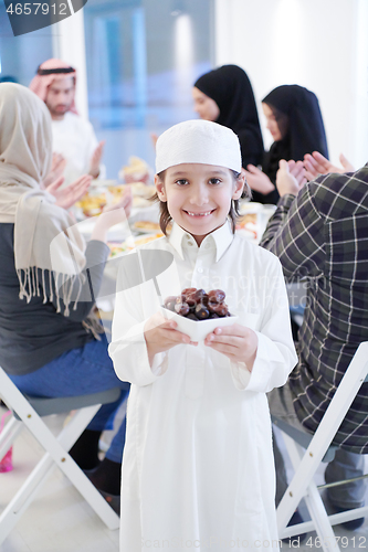 Image of little muslim boy holding a plate full of sweet dates