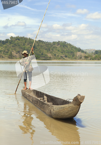 Image of Dak Lak, VIETNAM - JANUARY 6, 2015 - Man pushing a boat with a pole