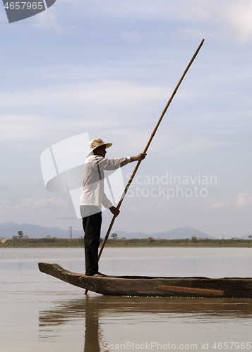 Image of Dak Lak, VIETNAM - JANUARY 6, 2015 - Man pushing a boat with a pole