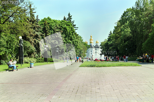 Image of People have a rest in park with big trees and fountains