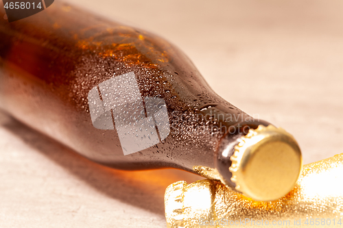 Image of a bottle of beer amber lying with its capsule