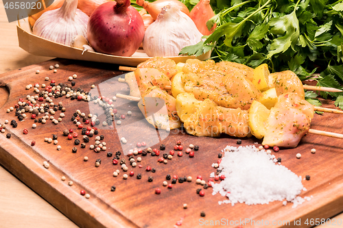 Image of raw chicken skewers marinated with lemon on a wooden board