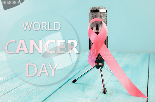 Image of the text world cancer day and a pink ribbon on a table background