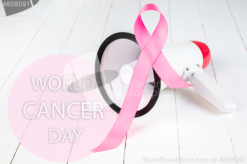 Image of the text world cancer day and a pink ribbon on a table background
