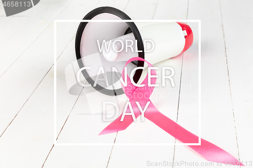 Image of the text world cancer day and a pink ribbon on a table background