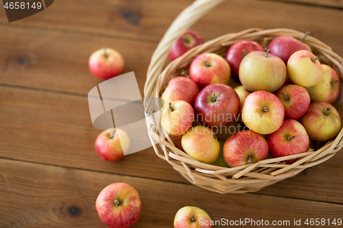 Image of ripe apples in wicker basket on wooden table