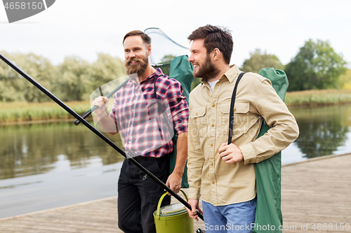 Image of male friends with net and fishing rods on lake