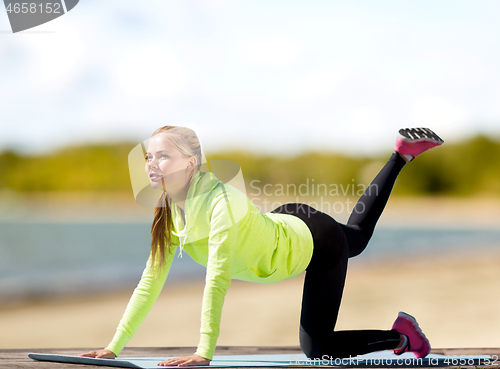 Image of woman training on exercise mat on beach