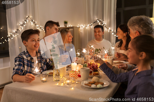 Image of family with sparklers having dinner party at home