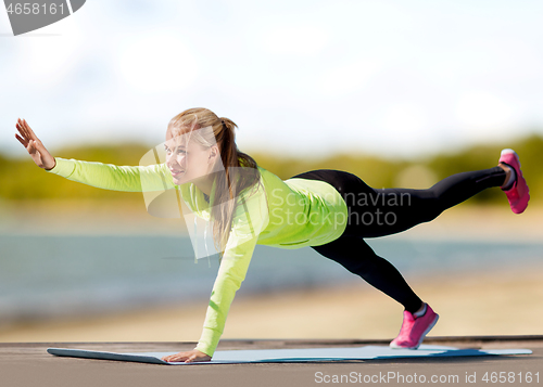 Image of woman training on exercise mat on beach