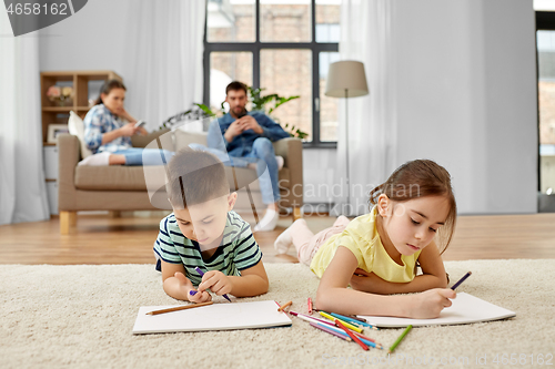 Image of brother and sister drawing with crayons at home