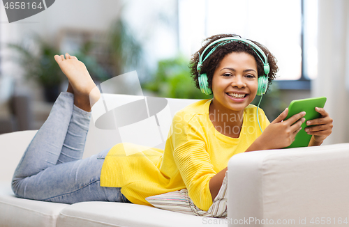 Image of happy african woman with tablet pc and headphones