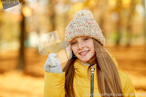 Image of portrait of girl with maple leaf at autumn park