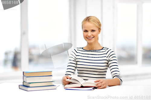 Image of smiling student woman with books learning at home