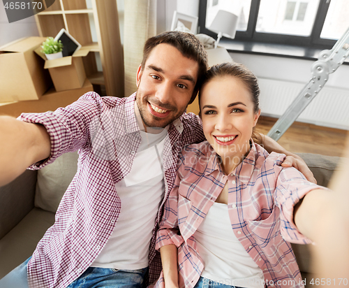 Image of happy couple taking selfie at new home