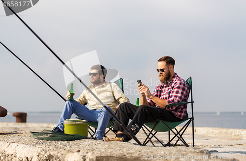 Image of friends with smartphone fishing and drinking beer