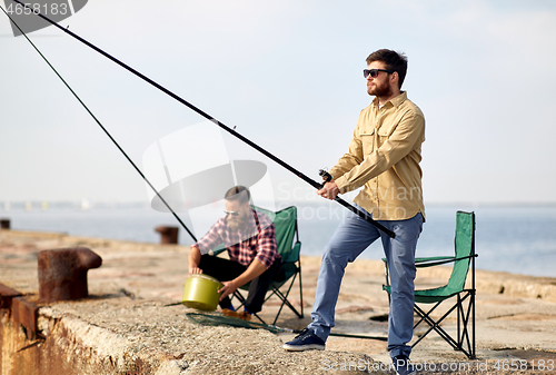 Image of happy friends with fishing rods on pier