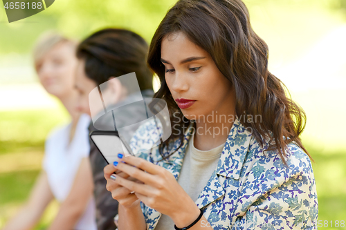 Image of woman using smartphone with friends at summer park