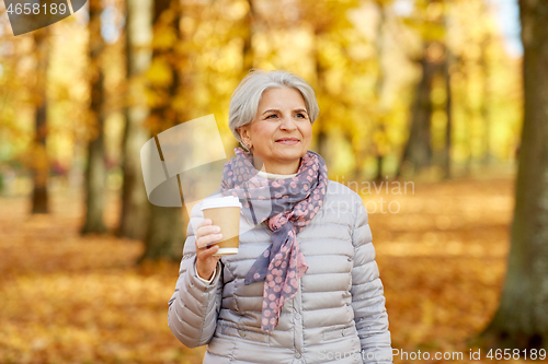 Image of senior woman drinking coffee in autumn park