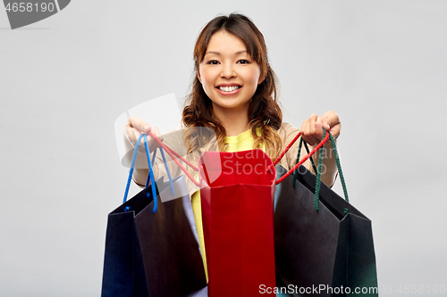 Image of happy asian woman with open shopping bags