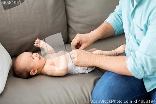 Image of middle aged father changing baby\'s diaper at home