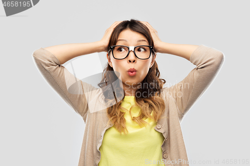 Image of asian female student in glasses holding to head